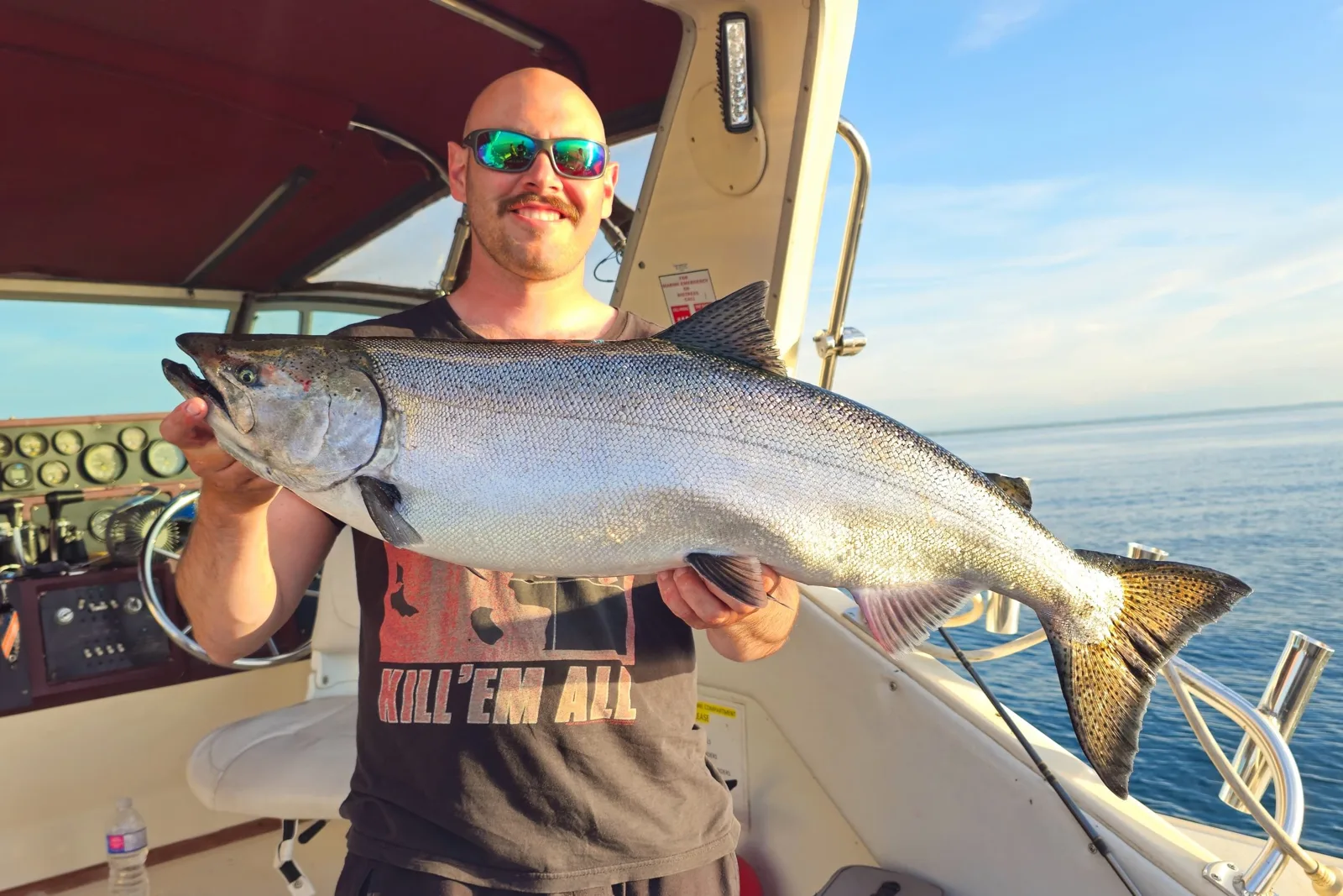 Angler at the helm of a King Slayer boat holding a steelhead