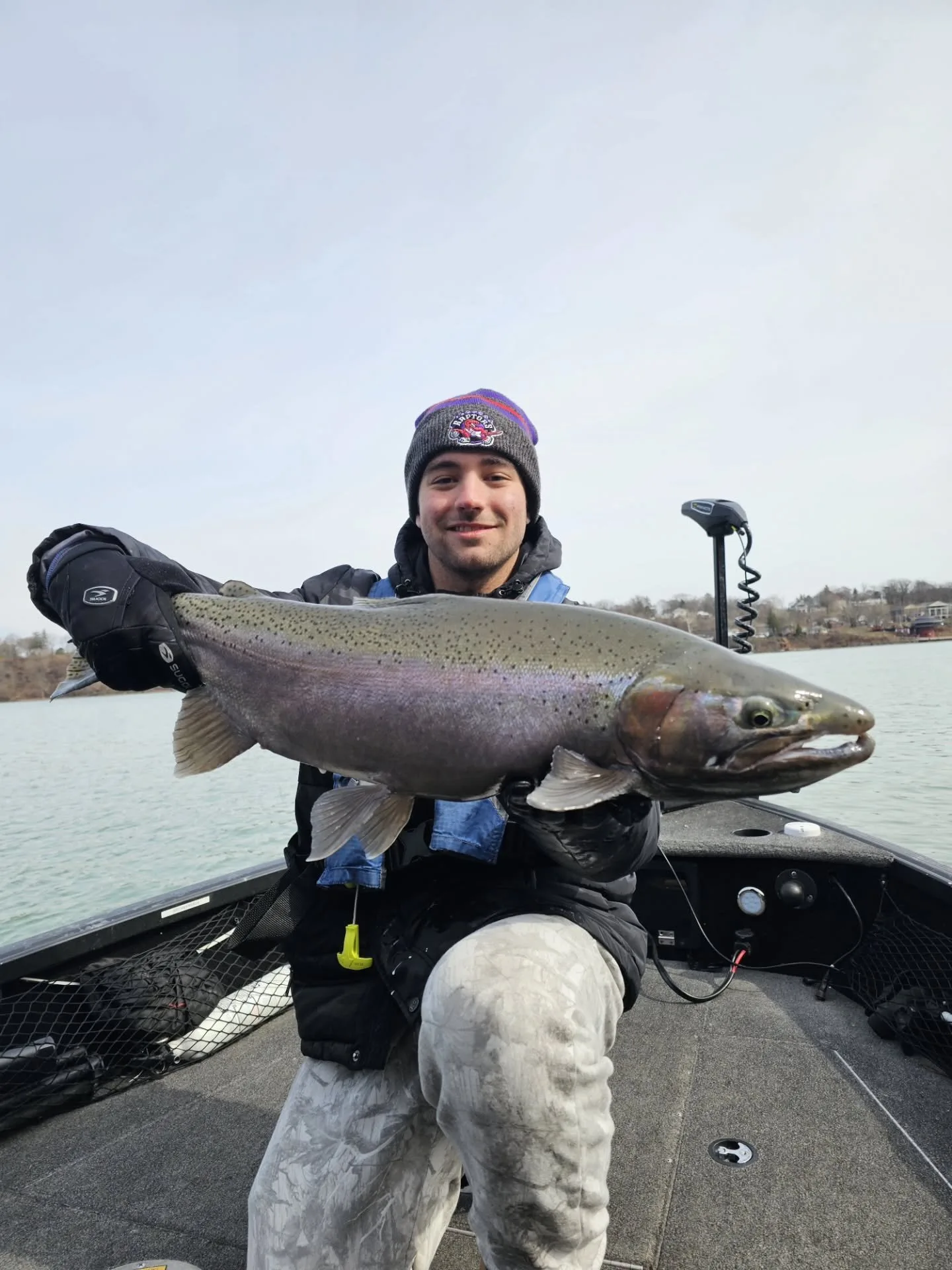 Angler holding a steelhead on a cloudy day on the river