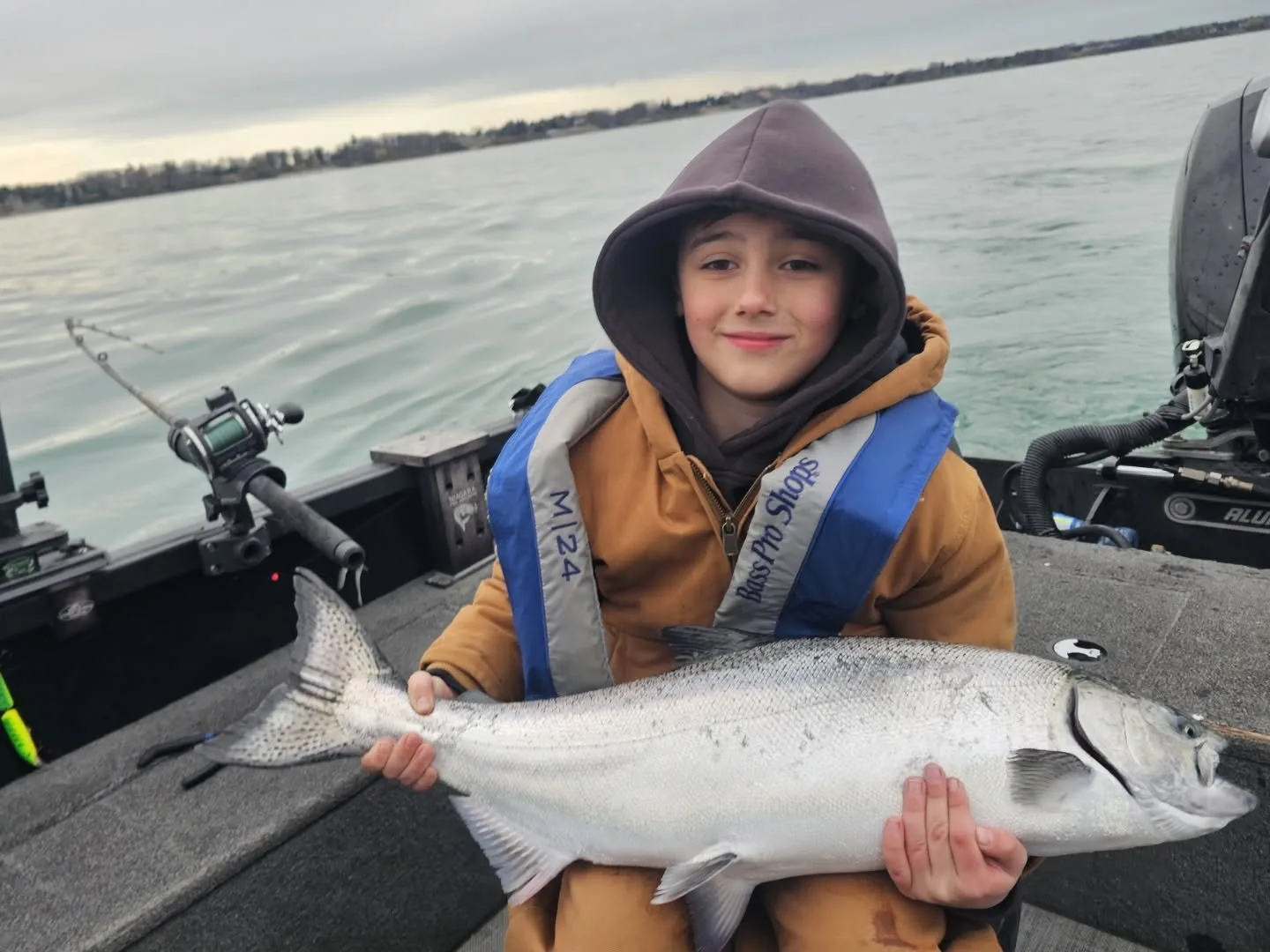 A young angler holding his chinook salmon catch aboard the charter