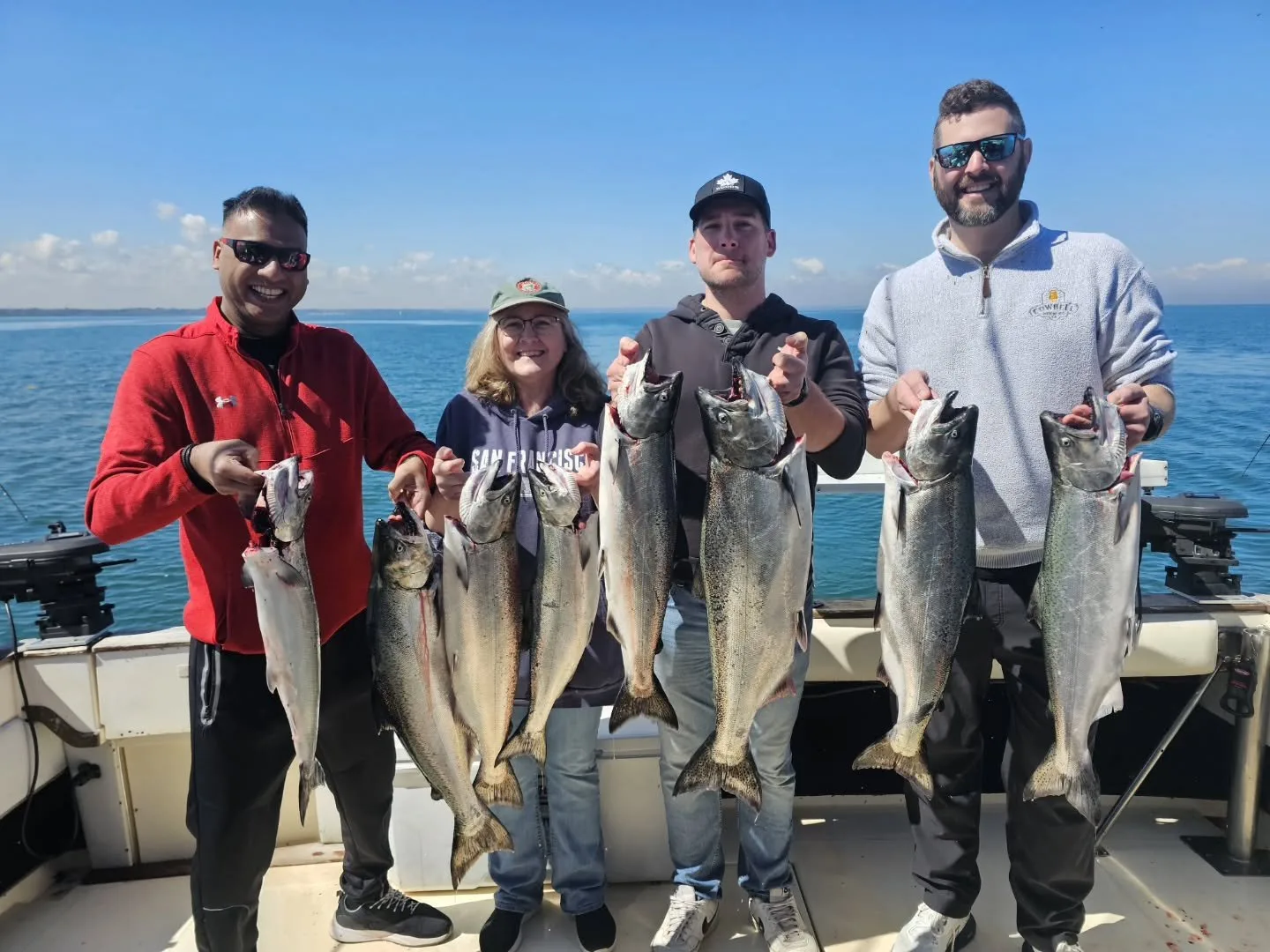 Four guests lined up on the back deck holding the day's catch after a King Slayer charter
