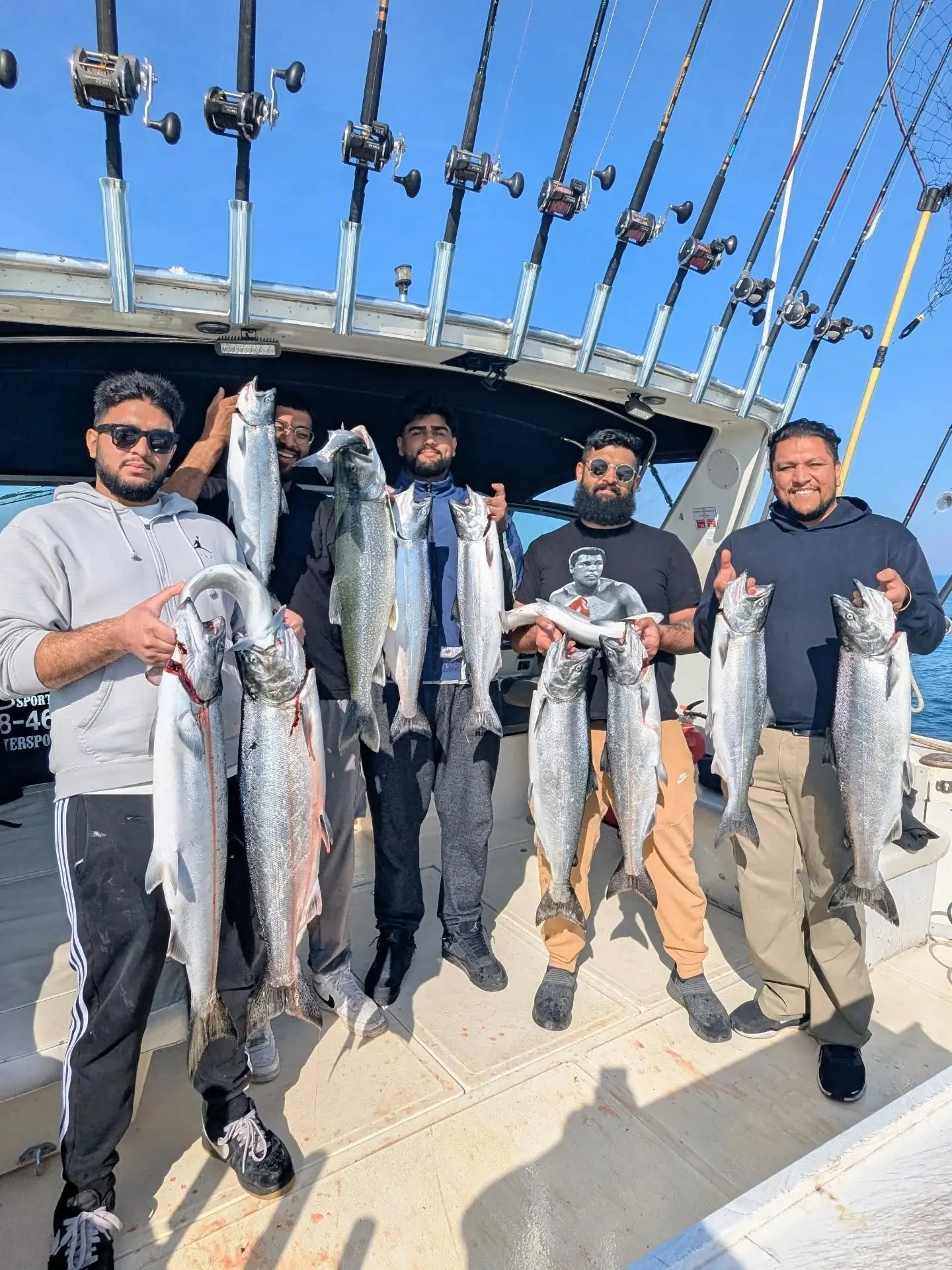 Five anglers holding a mixed catch of lake trout and salmon aboard King Slayer