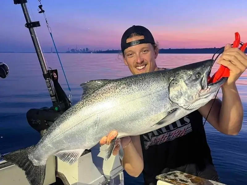 Captain Devin Winstanley holding a chinook salmon at sunset